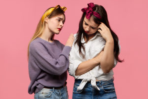 Support and care concept. Depressed girl crying because of break up with boyfriend while supportive female friend expressing sympathy, being sorry for her, saying Everything will be alright