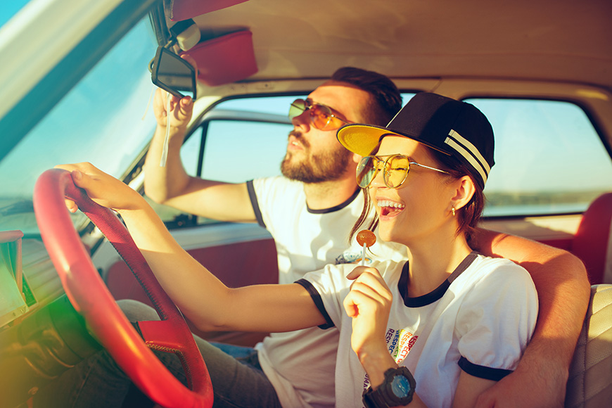 Laughing romantic couple sitting in car while out on a road trip at summer day