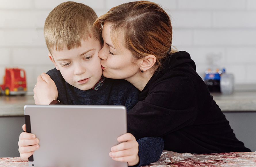 Mother using laptop and tablet teaching with her son online at h
